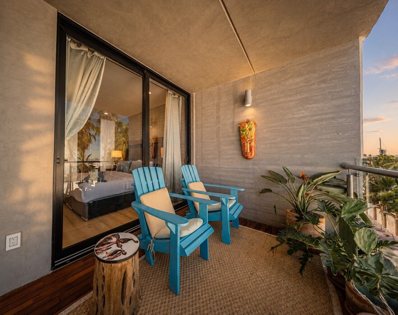 A balcony with two blue chairs, a small round table, and a potted plant.