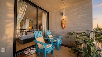 A balcony with two blue chairs, a small round table, and a potted plant.