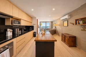 A modern kitchen with a central island, wooden cabinets, and a view to the outside.