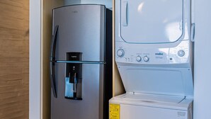 Una cocina compacta con un refrigerador de acero inoxidable integrado y una lavadora blanca.