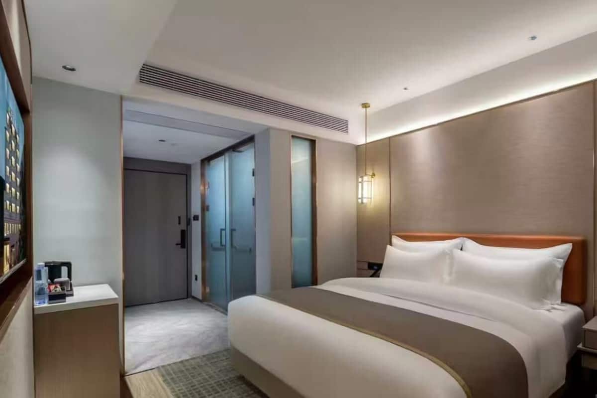 Una habitación de hotel moderna con una cama grande, una mesita de noche y una lámpara de pared.