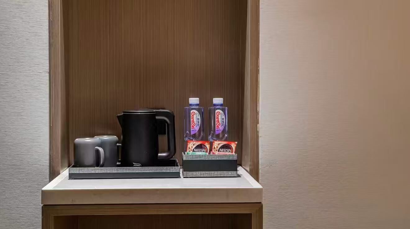 Ett litet köksutrymme med en kaffebryggare, två muggar och en vattenautomat.