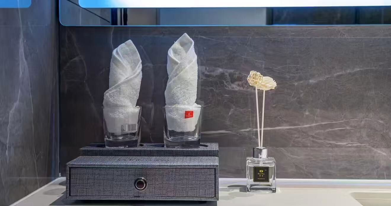 A minibar setup with two glasses of water, a bottle of water, and a decorative item.