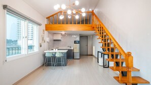 A modern apartment with a kitchen, dining area, and a wooden staircase. - Gangneung Comma Pension (Gangneung)