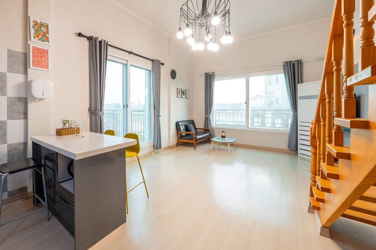 A modern apartment with a kitchen area, dining space, and a staircase.