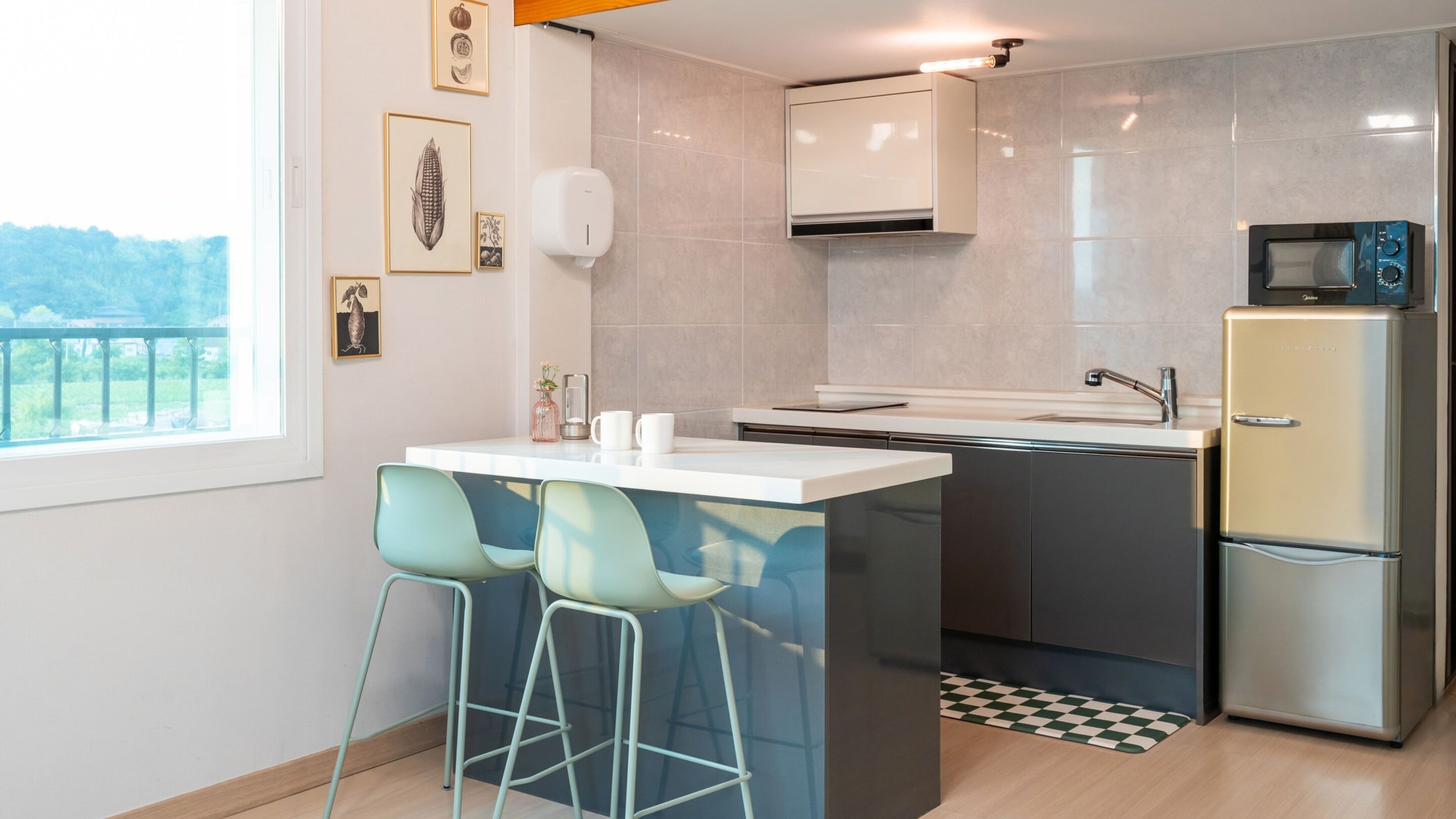 A modern kitchen with a white countertop, two bar stools, a microwave, and a refrigerator.