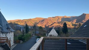 Eine Holzterrasse mit Blick auf eine Dorfstraße und Berge.