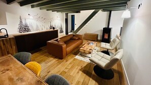 Ein modernes Wohnzimmer mit Holzboden, einem braunen Sofa, einem weißen Sessel, einem Couchtisch und einem Kamin.
