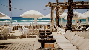 A beachside lounge with white umbrellas, lounge chairs, and a wooden deck. - Poleg Beach Seaview Stay by Sea N' Rent (Netanya)