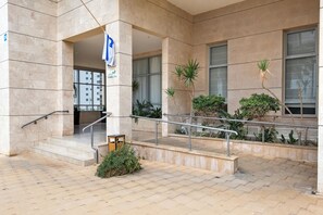 Entrada d'un edifici amb rampa, baranes i plantes en testos.