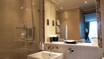 A modern bathroom with a glass-enclosed shower, a white sink, and a large mirror reflecting the room.