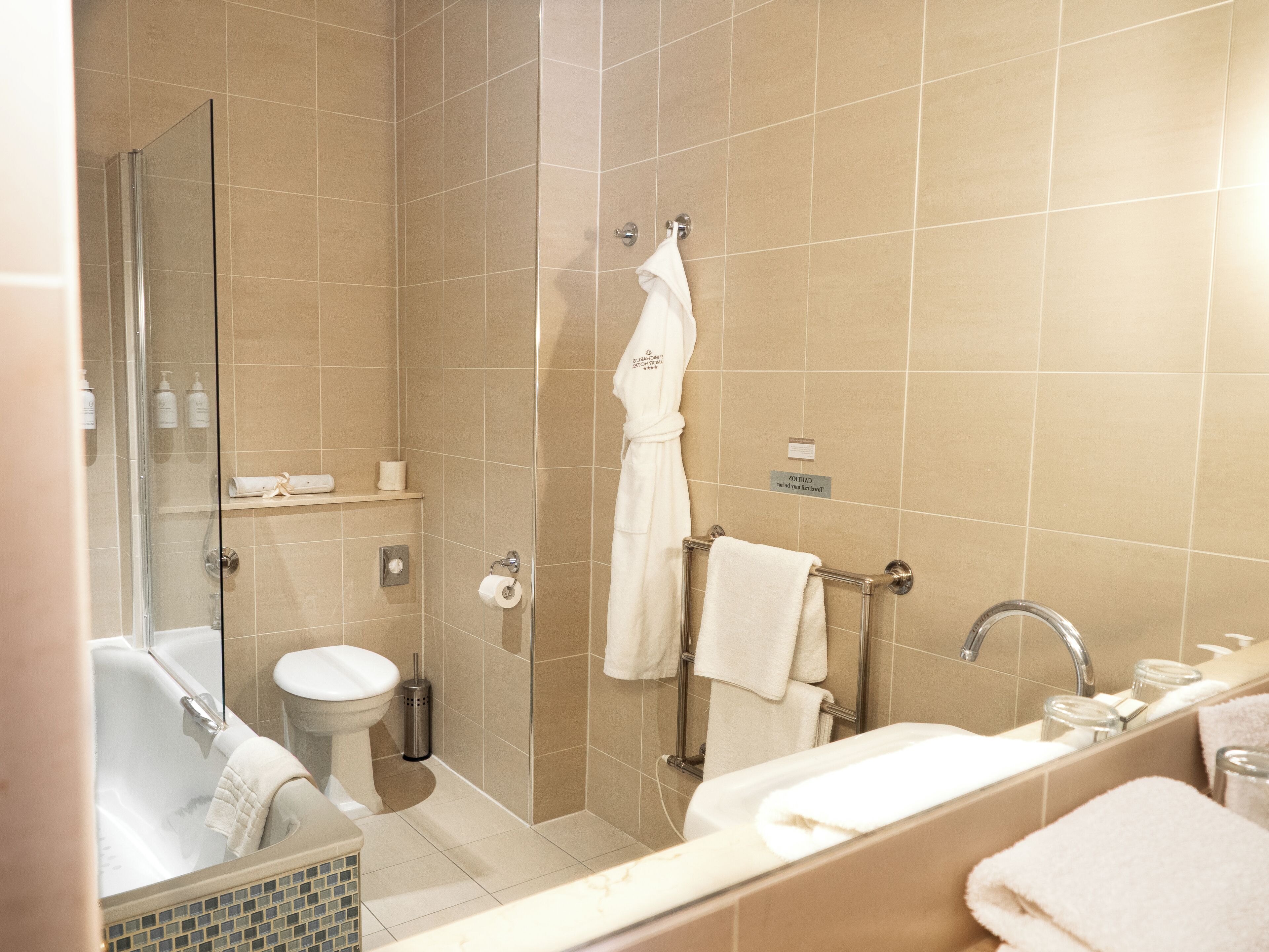 Un baño moderno con ducha de vidrio, inodoro blanco, bañera y lavamanos.