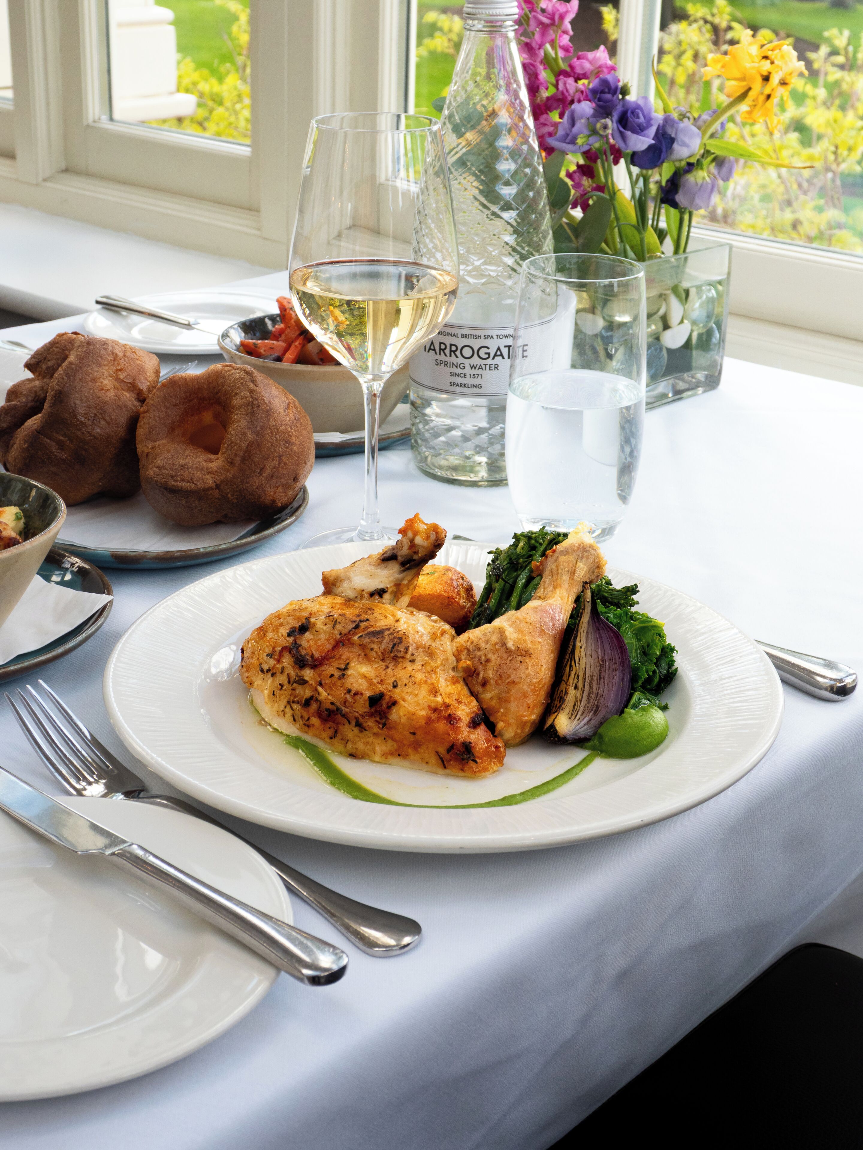 A dining table with a plate of food, a bottle of water, and a glass of wine.
