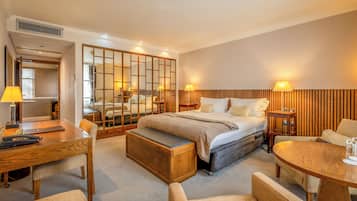 Una habitación de hotel con cama, mesitas de noche, un escritorio y una zona de estar.