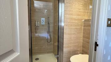 A modern bathroom with a glass-enclosed shower, a toilet, and a white door.