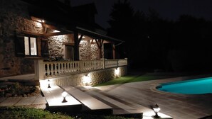 A stone house with a pool, stone walls, and a wooden deck.