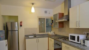 A compact kitchen with a refrigerator, microwave, stove, sink, and cabinets. - Near Juffair Oasis Mall / Tow Bedroom Apartment (Jaffer)