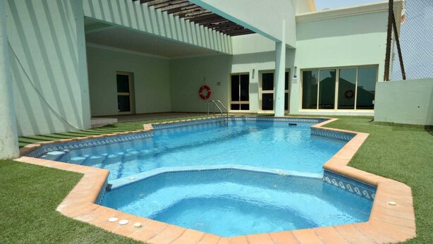 A swimming pool with a tiled edge and a brick border, surrounded by artificial grass. - Near Juffair Oasis Mall / Tow Bedroom Apartment (Jaffer)