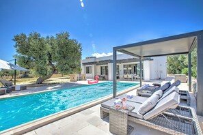 A pool area with lounge chairs and a covered seating area.