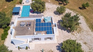 Vista aérea de una propiedad con piscina, paneles solares y mobiliario de exterior.