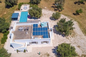 An aerial view of a property with a swimming pool, solar panels, and outdoor seating.