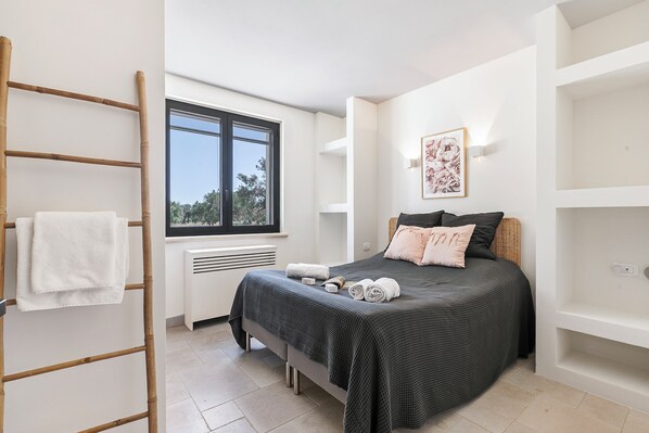 A bedroom with a bed, a window, a radiator, and a ladder.