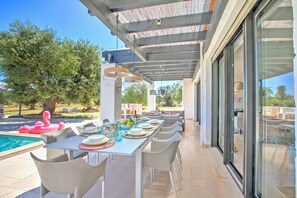 An outdoor dining area with a pool, dining tables, chairs, and a flamingo float.