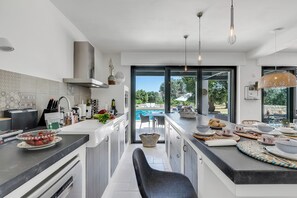 Eine moderne Küche mit Kochinsel, großen Fenstern und Blick auf einen Außenpool.