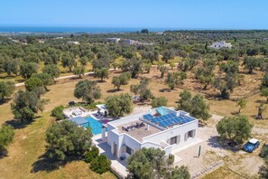 A modern house with a swimming pool, solar panels, and a view of the sea.