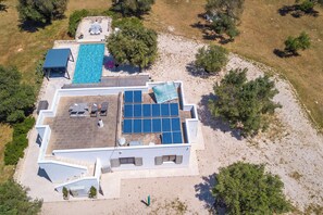An aerial view of a property with a swimming pool, solar panels, and outdoor seating.