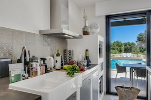 A modern kitchen with a large island, a view of a swimming pool, and a sign indicating 'HAPPY RENTALS'.