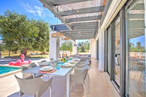 An outdoor dining area with a pool, tables, chairs, and a pergola.
