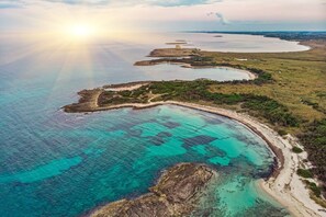An aerial view of a coastal area with clear turquoise waters, sandy beaches, and scattered vegetation. - Villa Tartaruga Luxury With Pool (Carovigno)