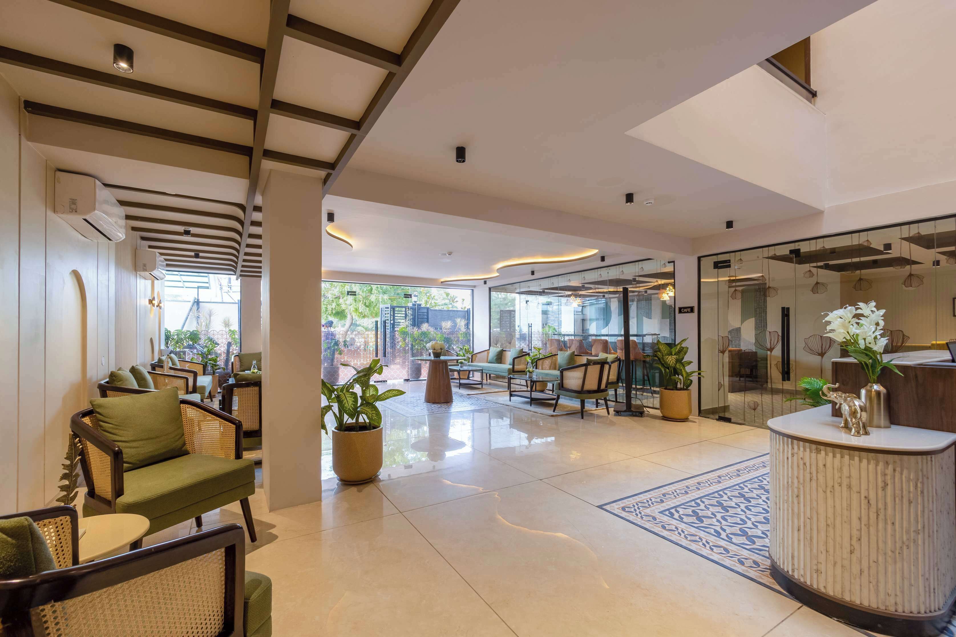 A hotel lobby with seating areas, a reception desk, and potted plants.
