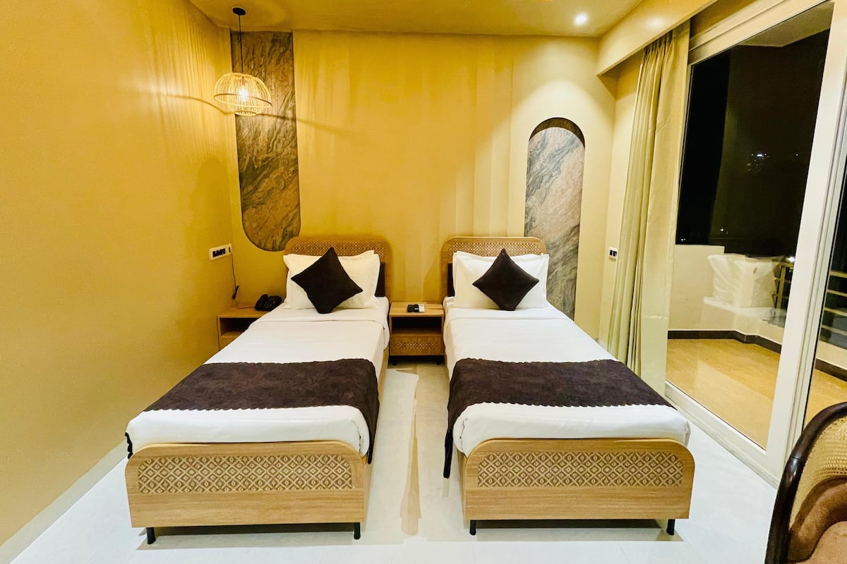 Ein Hotelzimmer mit zwei Betten, einer Marmorwand, einer Deckenleuchte und Blick ins Freie.