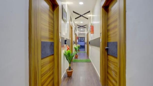 A hallway with wooden doors, ceiling fans, and potted plants.