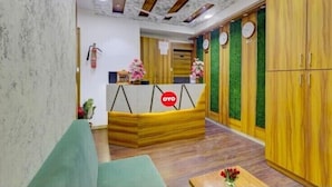 A reception area with a wooden reception desk, a green sofa, and a wooden wardrobe with clocks.