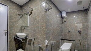 A modern bathroom with a marble wall, a sink, a toilet, and a shower.