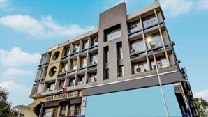 A multi-story hotel with a modern architectural design, featuring balconies and air conditioning units.