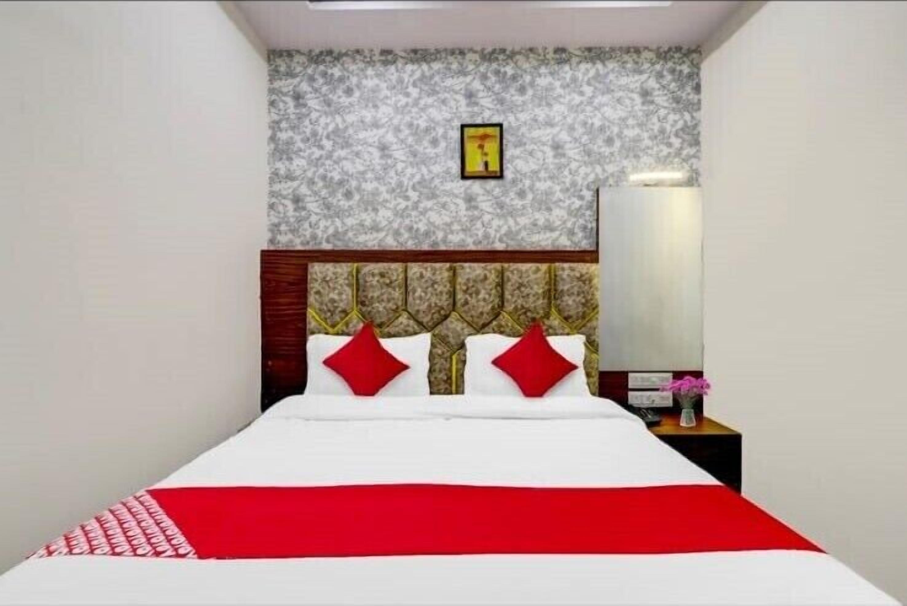 A neatly made bed with a red and white bedspread, a wooden headboard, and two red pillows.