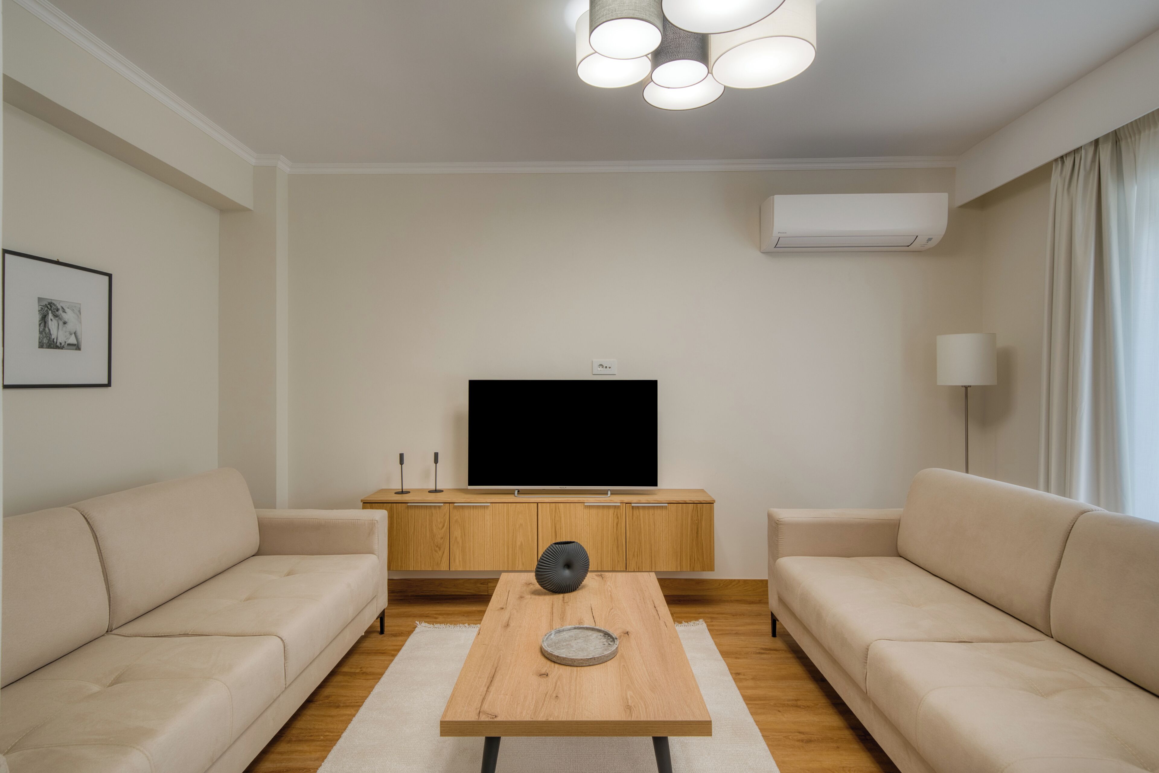 A modern living room with a flat-screen TV, two sofas, a coffee table, and a wooden cabinet.