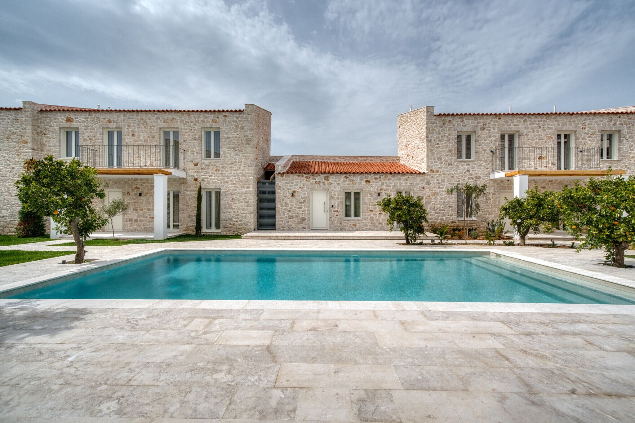 A two-story stone building with a swimming pool in front.