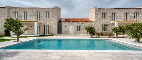 A two-story stone building with a swimming pool in front.