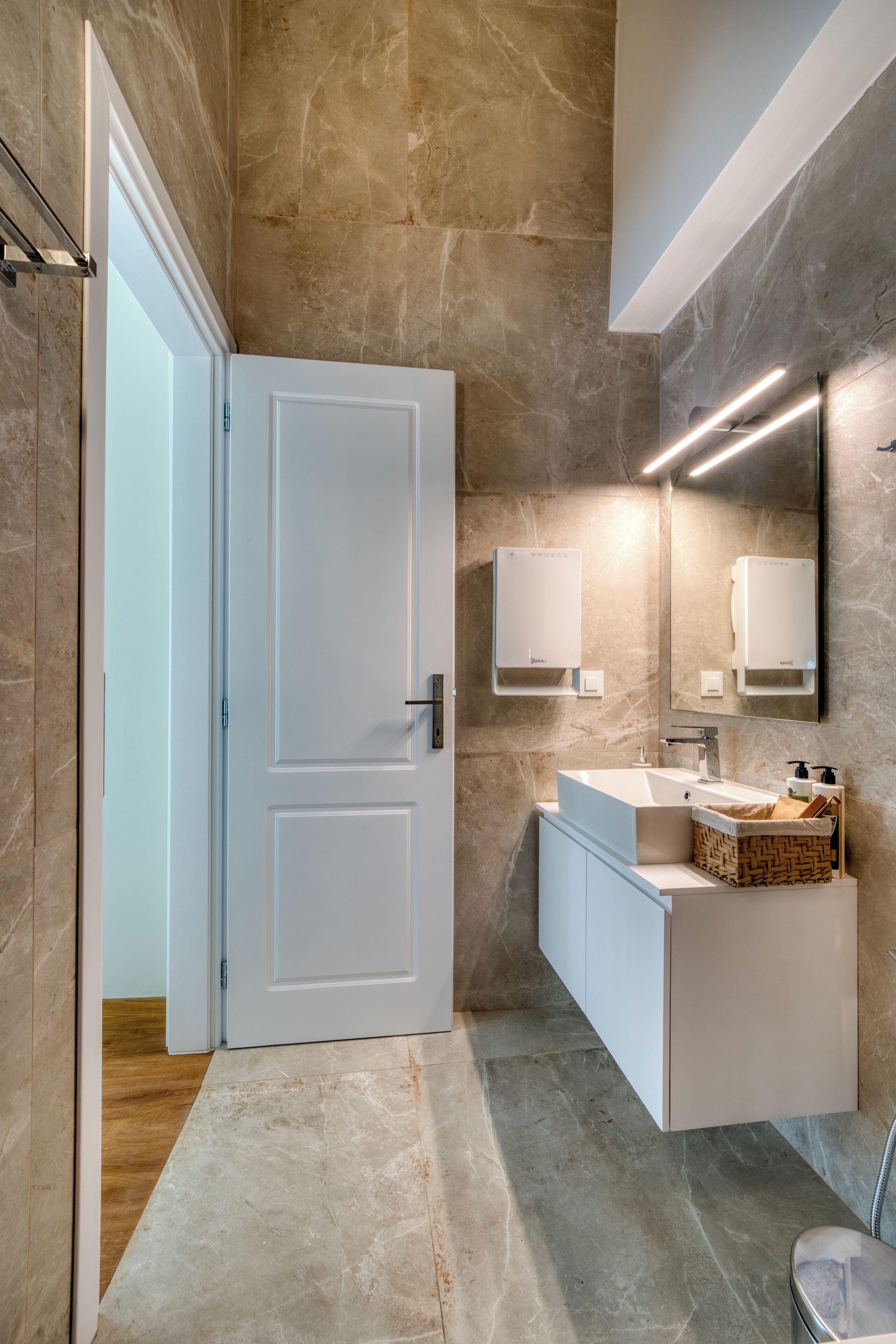 A modern bathroom with a white door, a built-in sink, and a mirror.