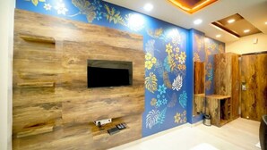 Een moderne woonkamer met een houten wandmeubel, een flatscreen-tv en een decoratieve bloemenmuur.