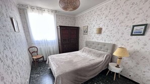A room with a bed, a chair, a lamp, and a door.