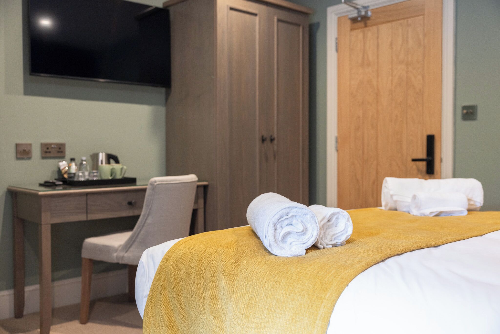 Una habitación de hotel con cama, escritorio, silla, armario y televisión.