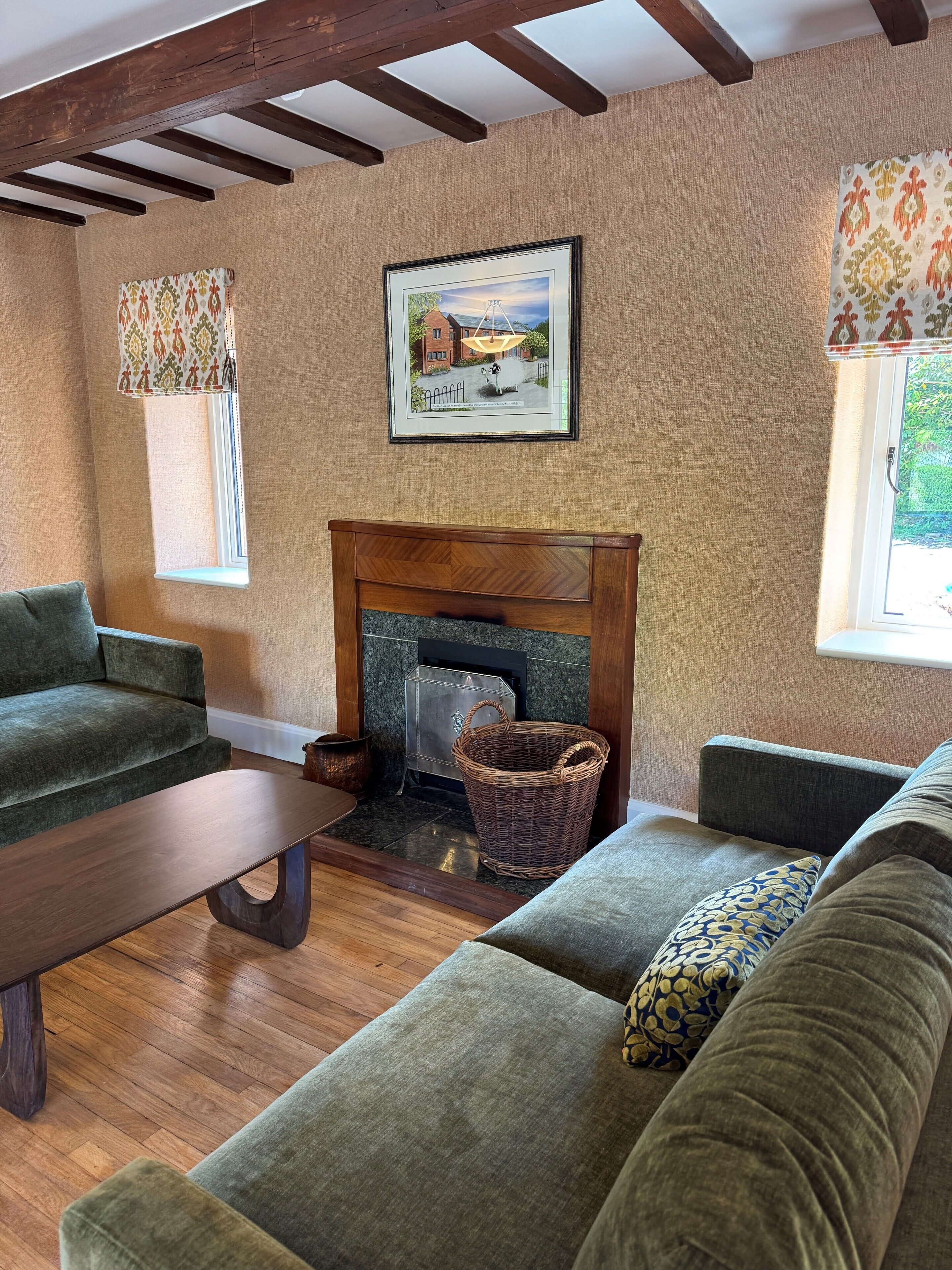 A cozy living room with a fireplace, green sofas, a wooden coffee table, and a framed picture on the wall.