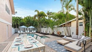 Ein Garten mit Pool, Sitzgelegenheiten im Freien und Palmen.