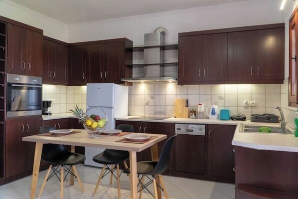 A modern kitchen with dark wooden cabinets, stainless steel appliances, and a central island with chairs.